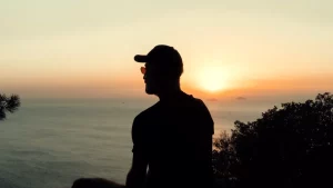 ظل رجل يتأمل البحر وقت الغروب في ضوء ذهبي هادئ