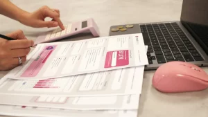 فواتير وآلة حاسبة وحاسوب محمول على مكتب ترمز إلى تنظيم مواعيد دفع الفواتير