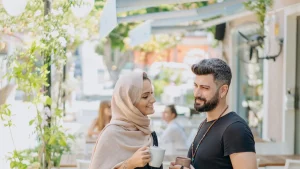 شاب وفتاة يتحدثان بهدوء في الشارع حاملين القهوة يرمزان إلى الحديث عن المال قبل الخطوبة